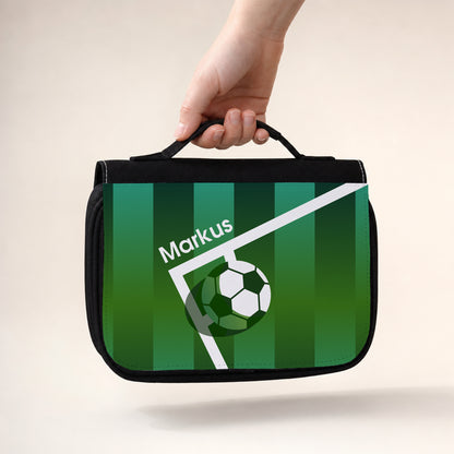 Personalisierter schwarzer Kulturbeutel mit Fußball-Aufdruck, Spielfeld-Motiv und Name Markus, getragen am Griff