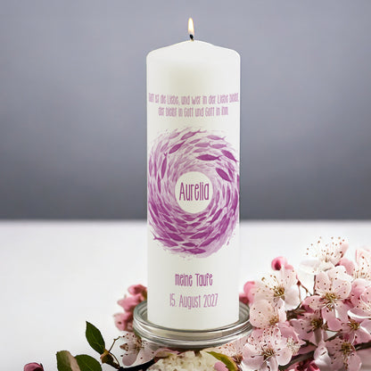 Rosa Fischschwarm-Kerze zur Taufe mit personalisiertem Namen – Eine zart gestaltete Taufkerze mit einem schwungvollen Fischschwarm in Violett- und Rosatönen. In der Mitte befindet sich der Name des Täuflings, während oben ein biblischer Spruch zur Liebe abgebildet ist. Die Beschriftung „Meine Taufe“ und das Datum sind unterhalb des Motivs. Die Kerze steht auf einem silbernen Halter, umgeben von blühenden rosa Kirschblüten.