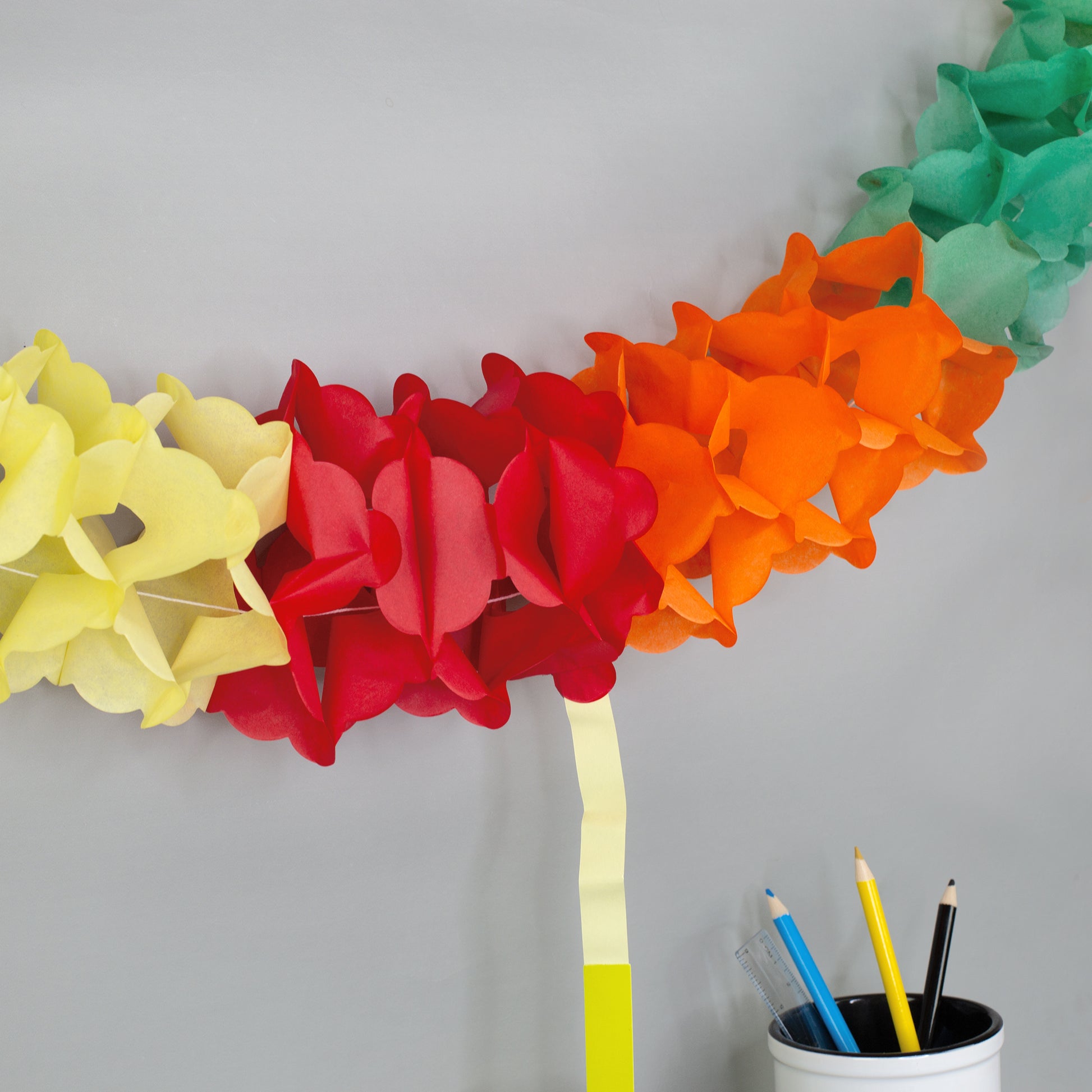 Detailansicht der bunten Papiergirlande mit roten, gelben, orangen und grünen Elementen