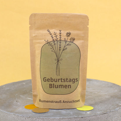 Geburtstagsblumen Anzuchtset im Kraftpapierbeutel mit schlichtem Blumenstrauß Motiv auf gelbem Hintergrund